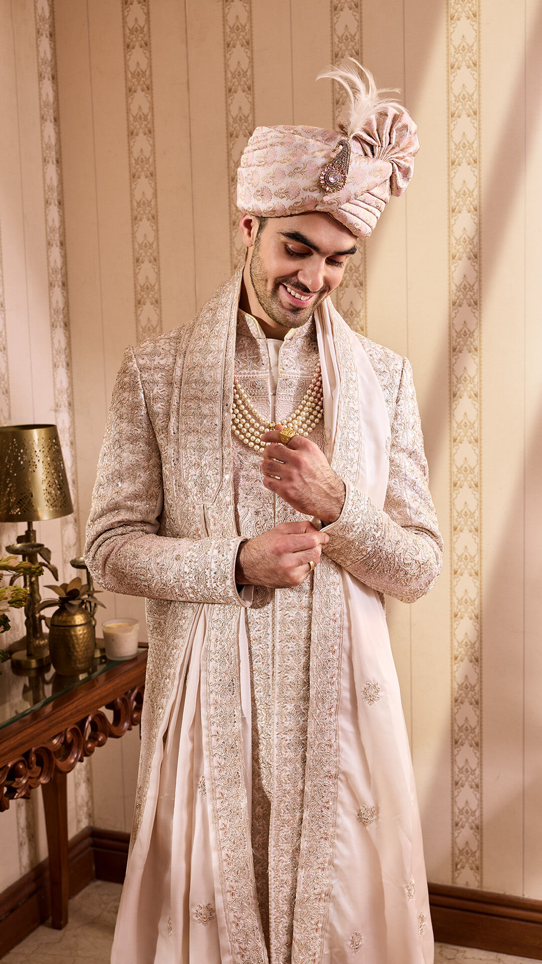 A stylish groom wearing an elegant sherwani and a matching turban, accessorized with a pearl necklace